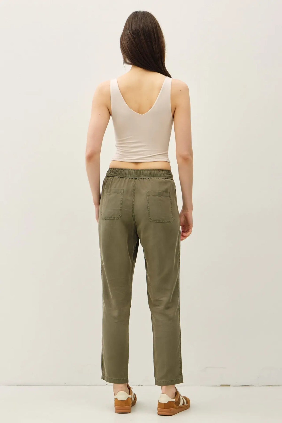 Woman wearing beige top and olive green TENCEL TAPERED PANTS showcasing stylish tapered pants