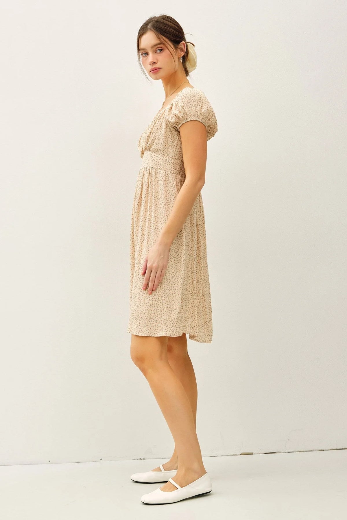 Woman wearing a floral print mini dress with puff sleeves and white ballet flats