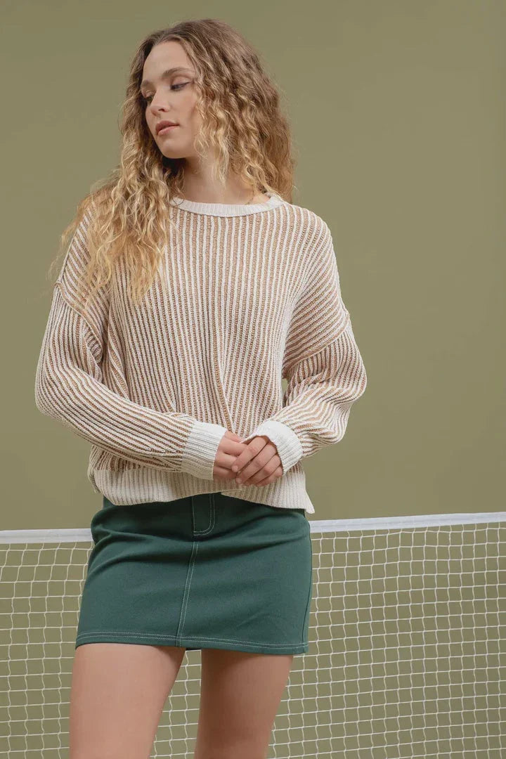 Woman in a beige ribbed sweater and green skirt from Shop Daisy’s women’s boho chic clothing