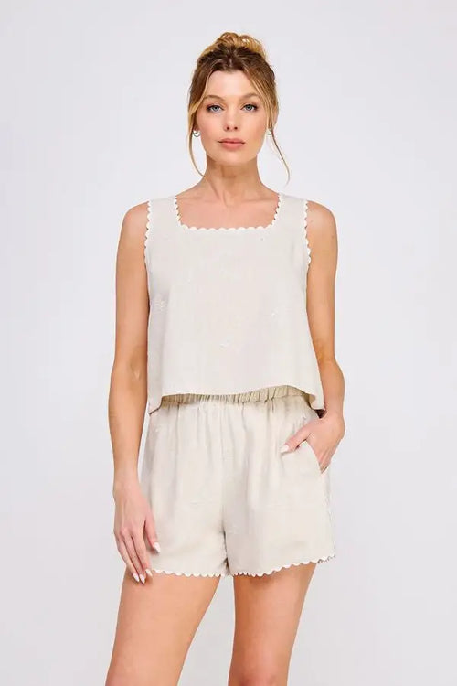 Woman wearing beige square neck tank with scalloped trim and ribbon details