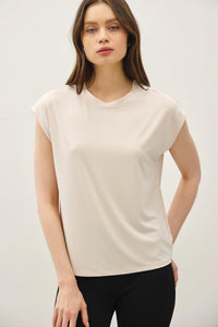 Woman wearing beige bamboo cap sleeve round neck basic top and black pants