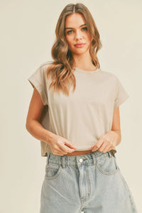 Woman wearing a beige round neck cuffed short-sleeve crop top and light-wash wide-leg jeans