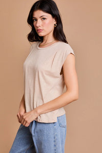 Woman in beige pleated shoulder top with blue jeans, showcasing a boho flowy style