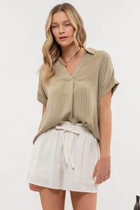 Woman in a beige striped collared split neck blouse and white skirt