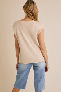 Woman wearing beige sleeveless top with wide shoulder USA flag sweater featuring shoulder USA flag design
