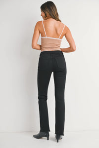 Woman from behind wearing mid rise flare denim jeans with raw hem and black ankle boots