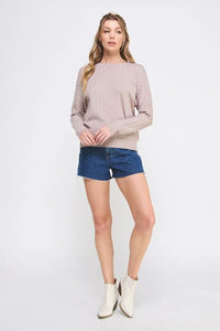 Woman in a beige cable knit pattern pointelle sweater and blue denim shorts