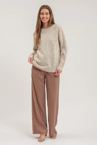 Woman in a beige speckle knit long sleeve sweater and brown wide-leg pants