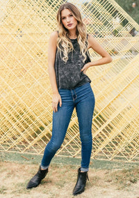Woman modeling black acid-wash cotton muscle tee with blue skinny jeans and black ankle boots