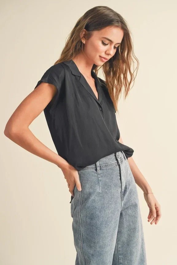 Woman in a black blouse and gray pants showcasing cap sleeve shirts fashion