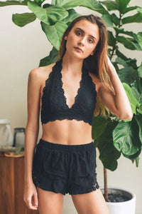 Woman in lined lace halter bralette and shorts posing confidently for a photo