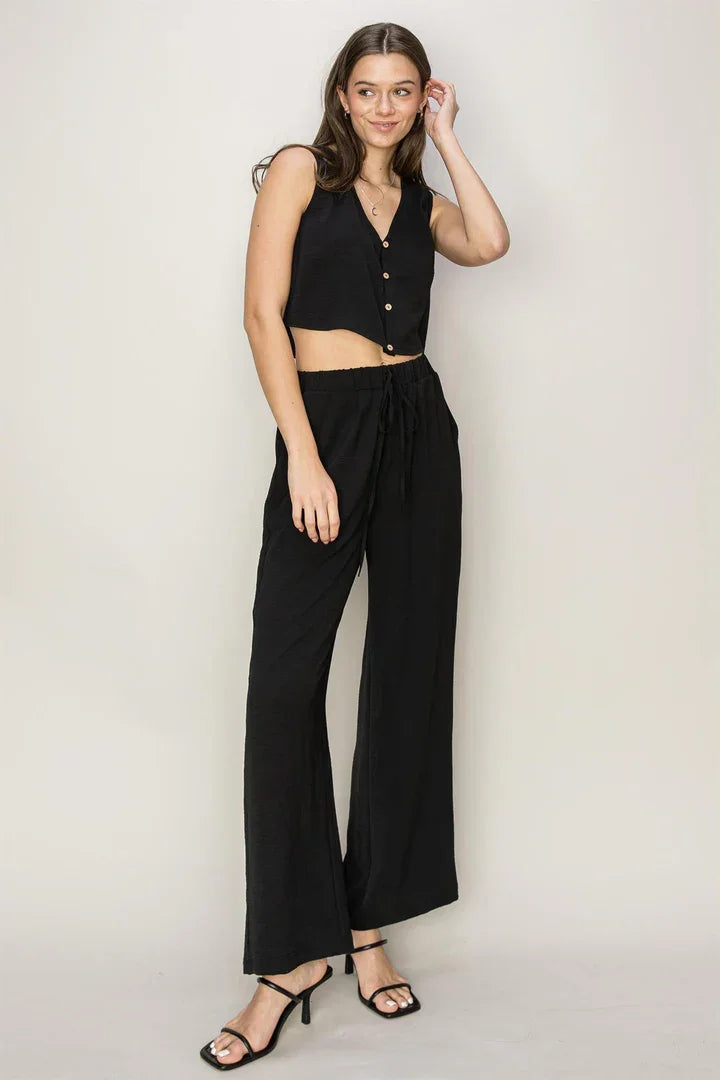 Woman in boho BUTTON-FRONT TOP AND PANTS SET, featuring a flowy black crop top