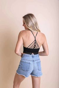 Woman in black top and denim shorts showcasing a high neck crochet lace trim bralette