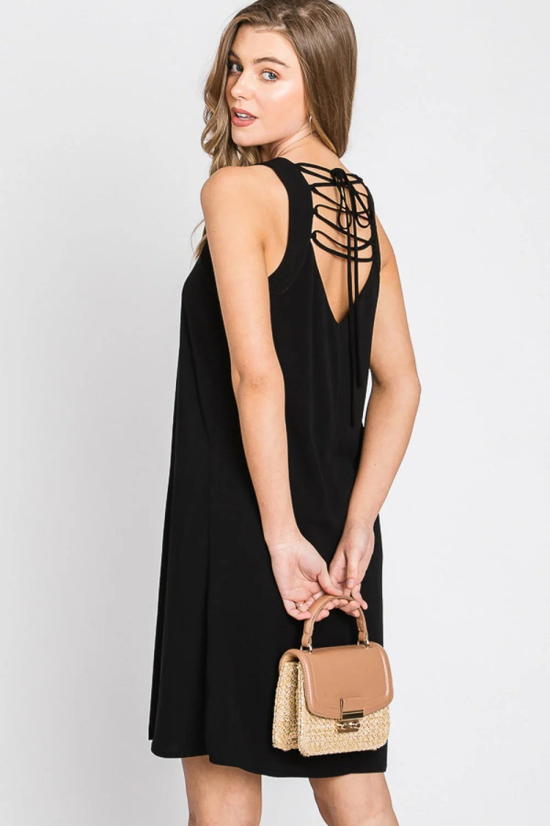 Woman modeling a black solid spaghetti strap dress with a lace back detail