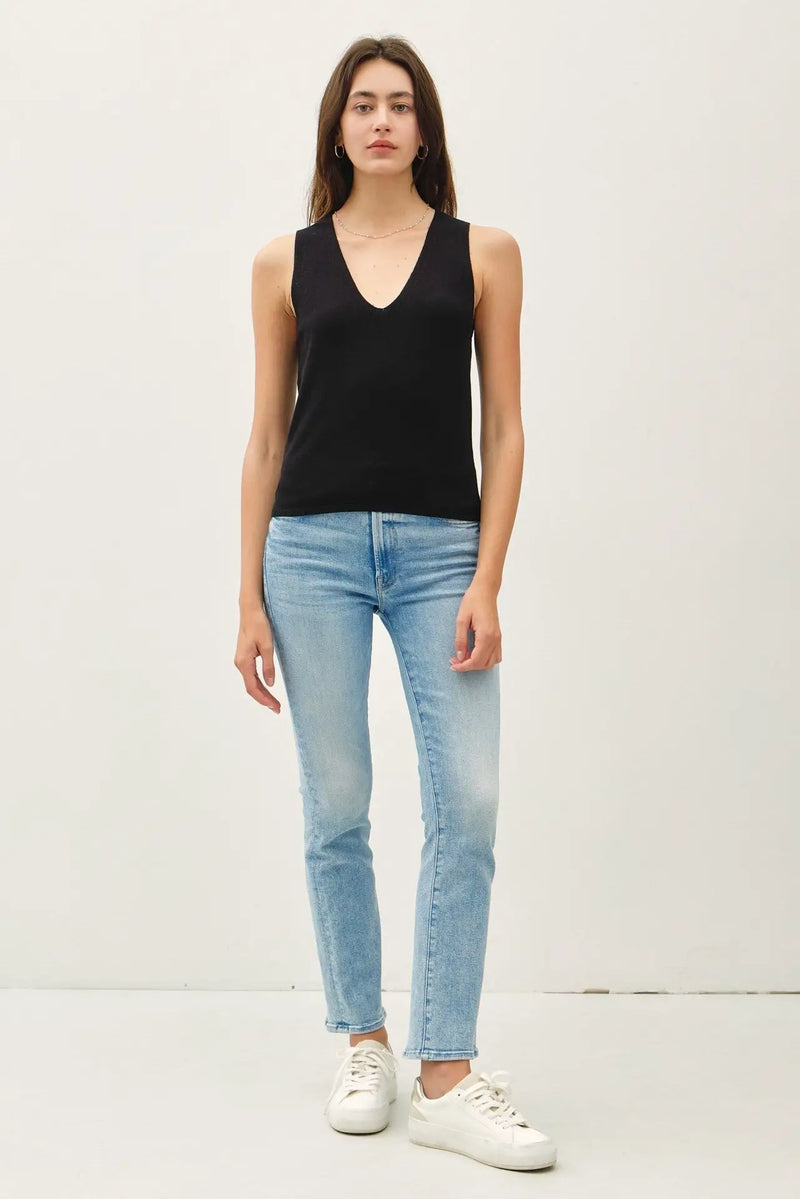 Woman in black sweater tank and jeans showcasing MINIMAL V NECK SWEATER TANK for women’s boho chic clothing at Shop Daisy