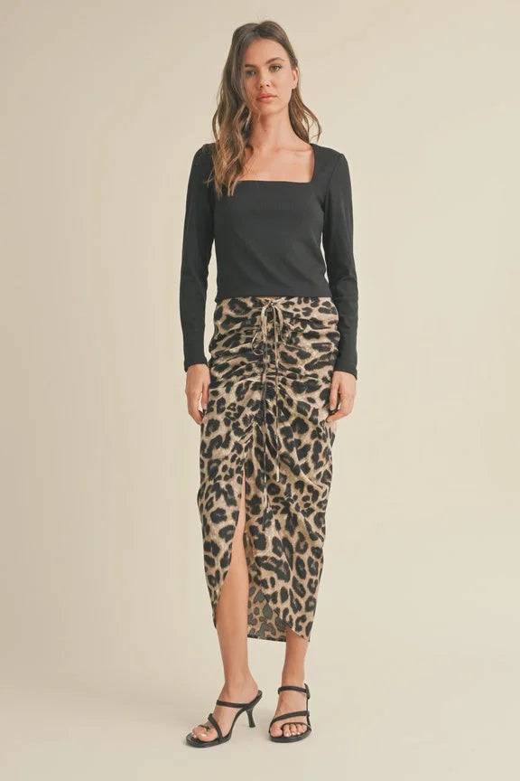 Woman in a black top and leopard print ruching detail skirt with front slit