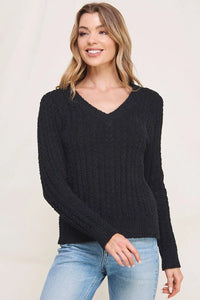 Woman wearing a soft cloud ribbed V-neck pullover sweater and light wash jeans