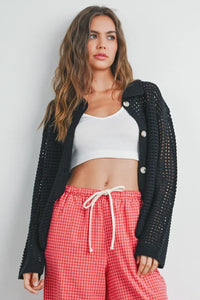 Woman wearing open stitch crochet collar cardigan with white crop top and red checkered pants