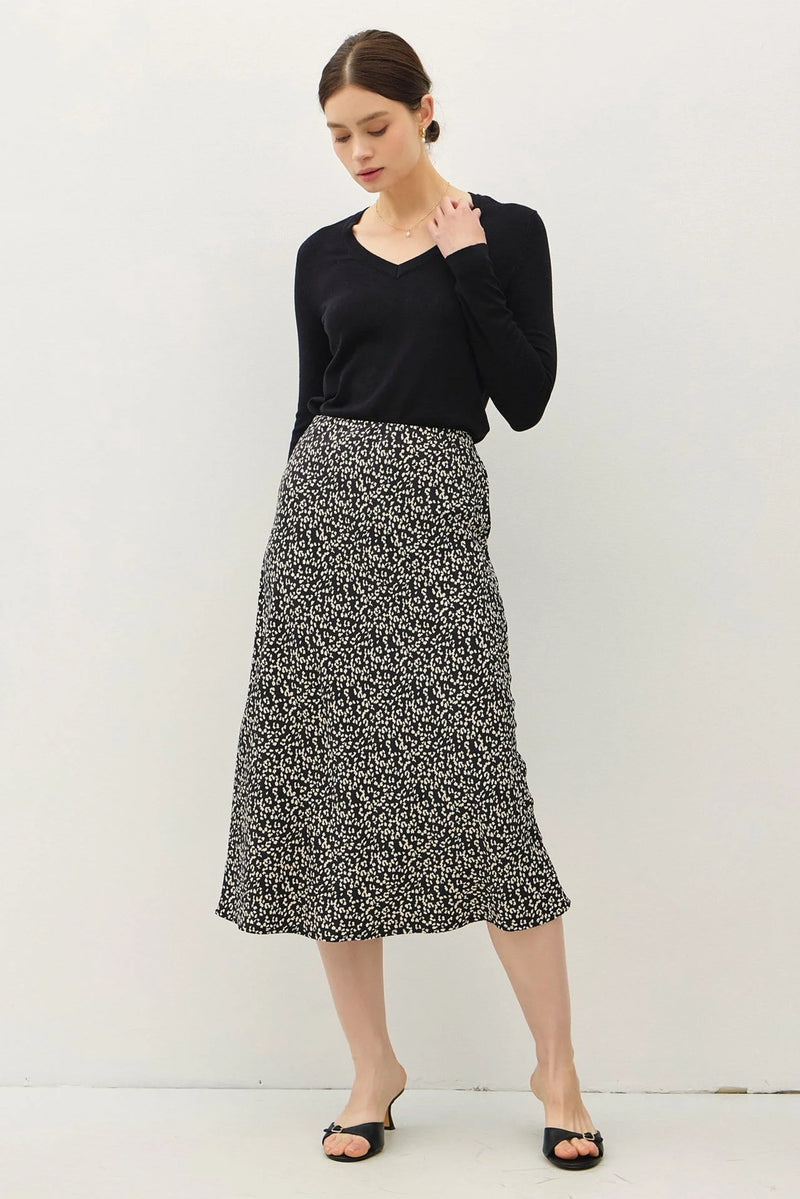 Woman in a black top and sandals wearing a stylish print midi skirt with elastic waistband