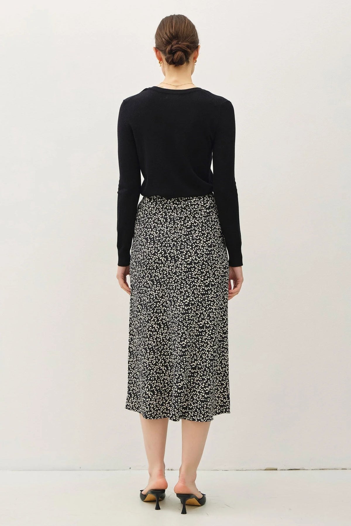 Woman in black top showcasing a stylish print midi skirt with elastic waistband