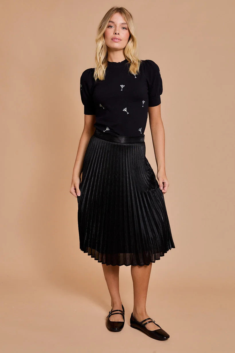 Woman in a black pleated skirt and embellished MOCK NECK HALF SLEEVE MARTINI top from Shop Daisy