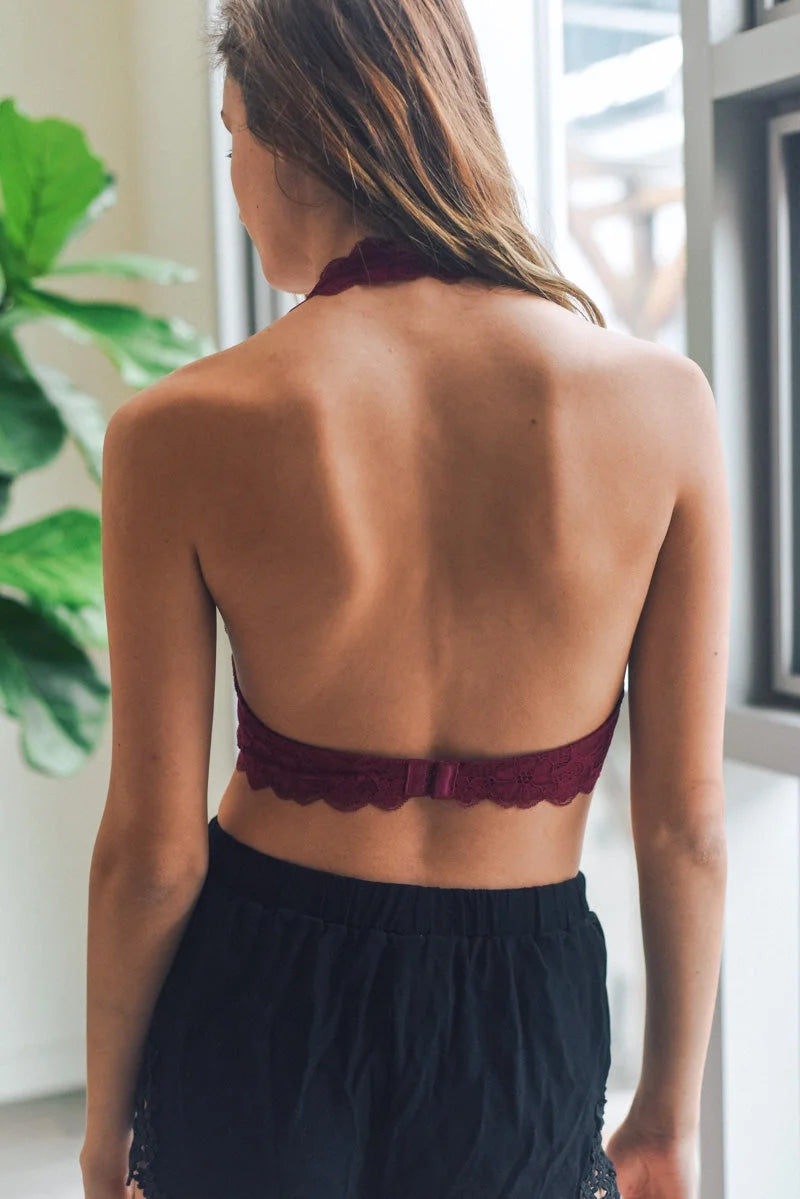 Woman wearing a Lined Lace Halter Top Bralette by a window, showcasing elegant design