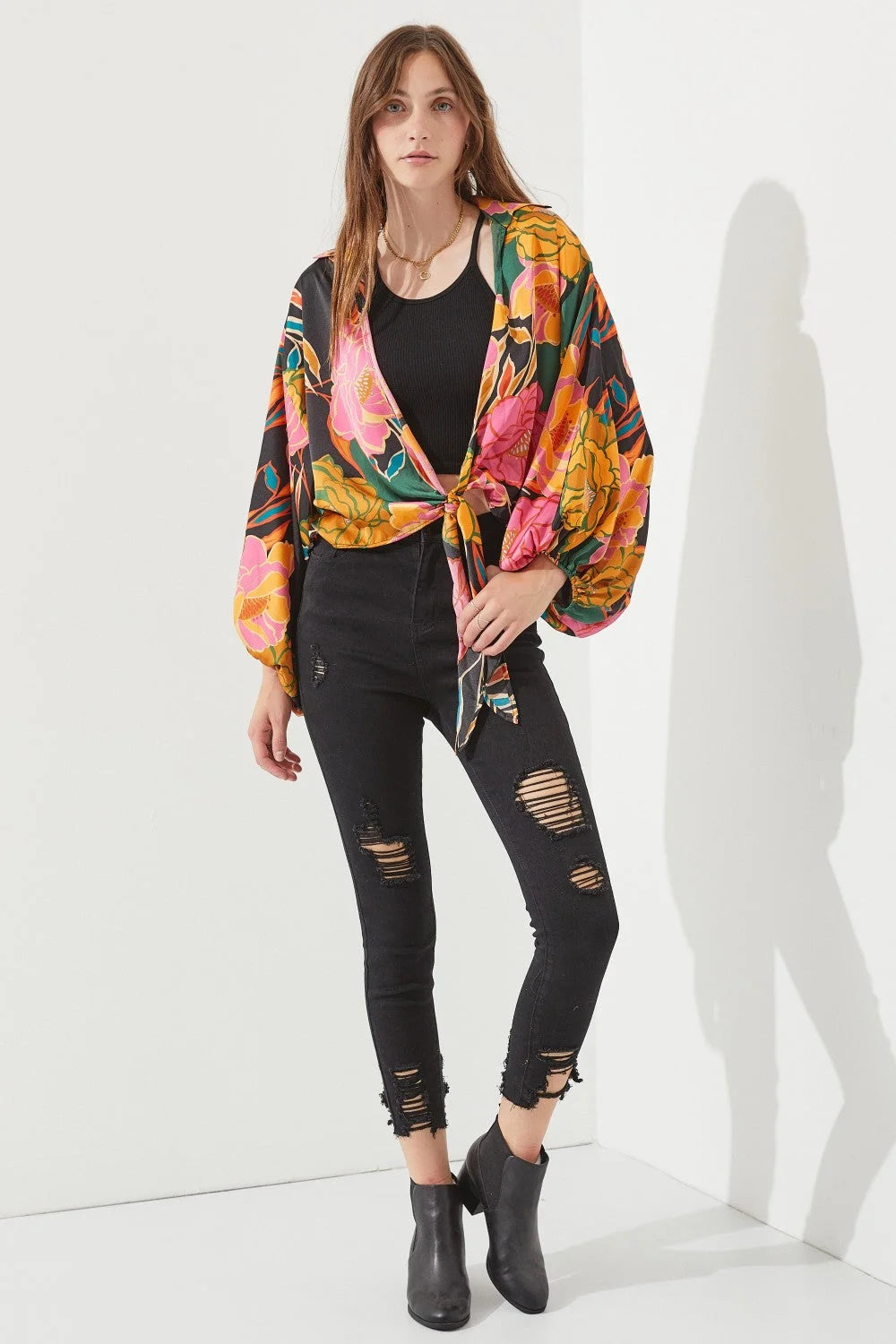 Woman in a black top and ripped jeans showcasing the Floral Print Tie-Front Cardigan