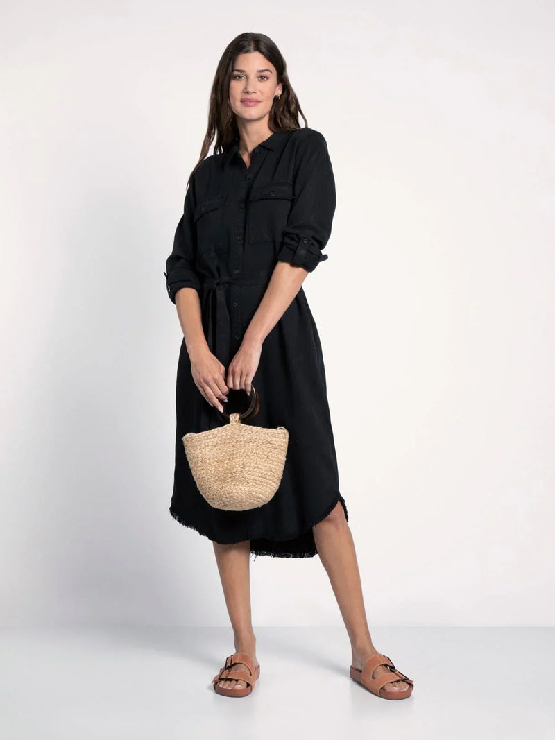 Woman in a black shirt denim midi dress with a woven straw handbag