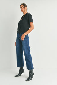 Woman in black shirt and high-heeled boots showcasing SLIM WIDE LEG DENIM, perfect for free spirit style