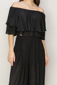 Woman in a black off the shoulder top and skirt, showcasing a stylish palazzo pants set