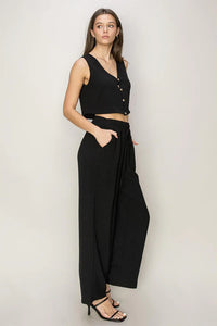 Woman in a black sleeveless crop top and flowy wide-leg pants set for a boho style