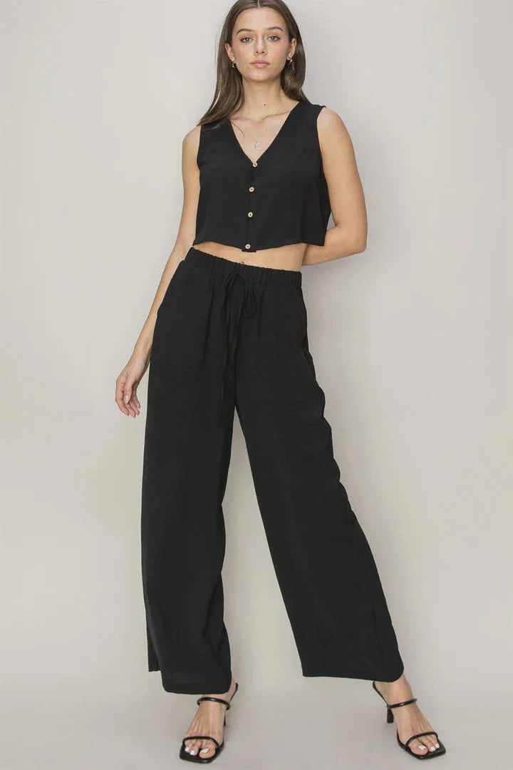 Woman in a black sleeveless crop top and wide-leg pants, embracing a boho, free spirit style