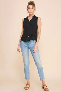 Woman wearing a sleeveless collared shirt with black top and light blue jeans