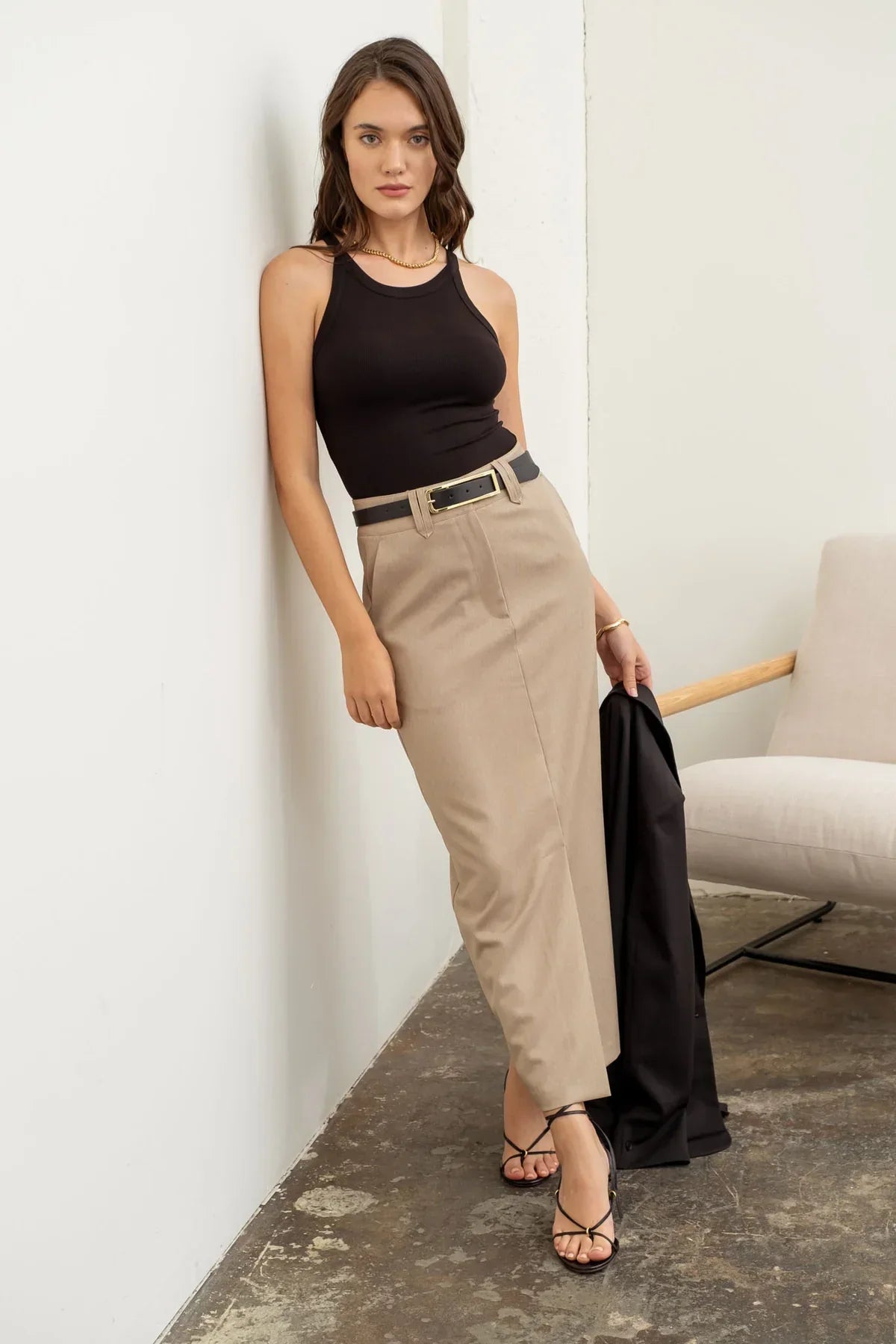 Woman in a black sleeveless top and beige skirt for a boho free spirit look