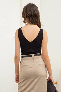 Woman in a black ribbed tank top and beige skirt, showcasing a boho style from behind