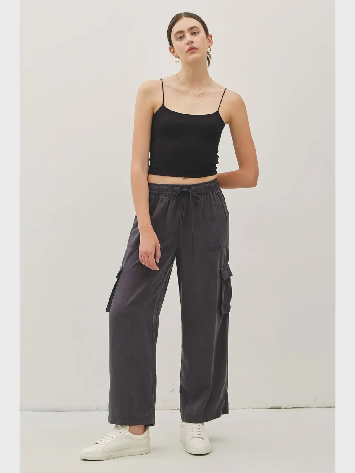 Woman wearing high rise drawstring wide leg cargo pants and a black spaghetti strap crop top