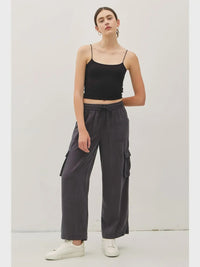 Woman wearing high rise drawstring wide leg cargo pants and a black spaghetti strap crop top