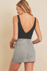 Woman in black tank top and denim skirt showcasing a double plunging bodysuit style