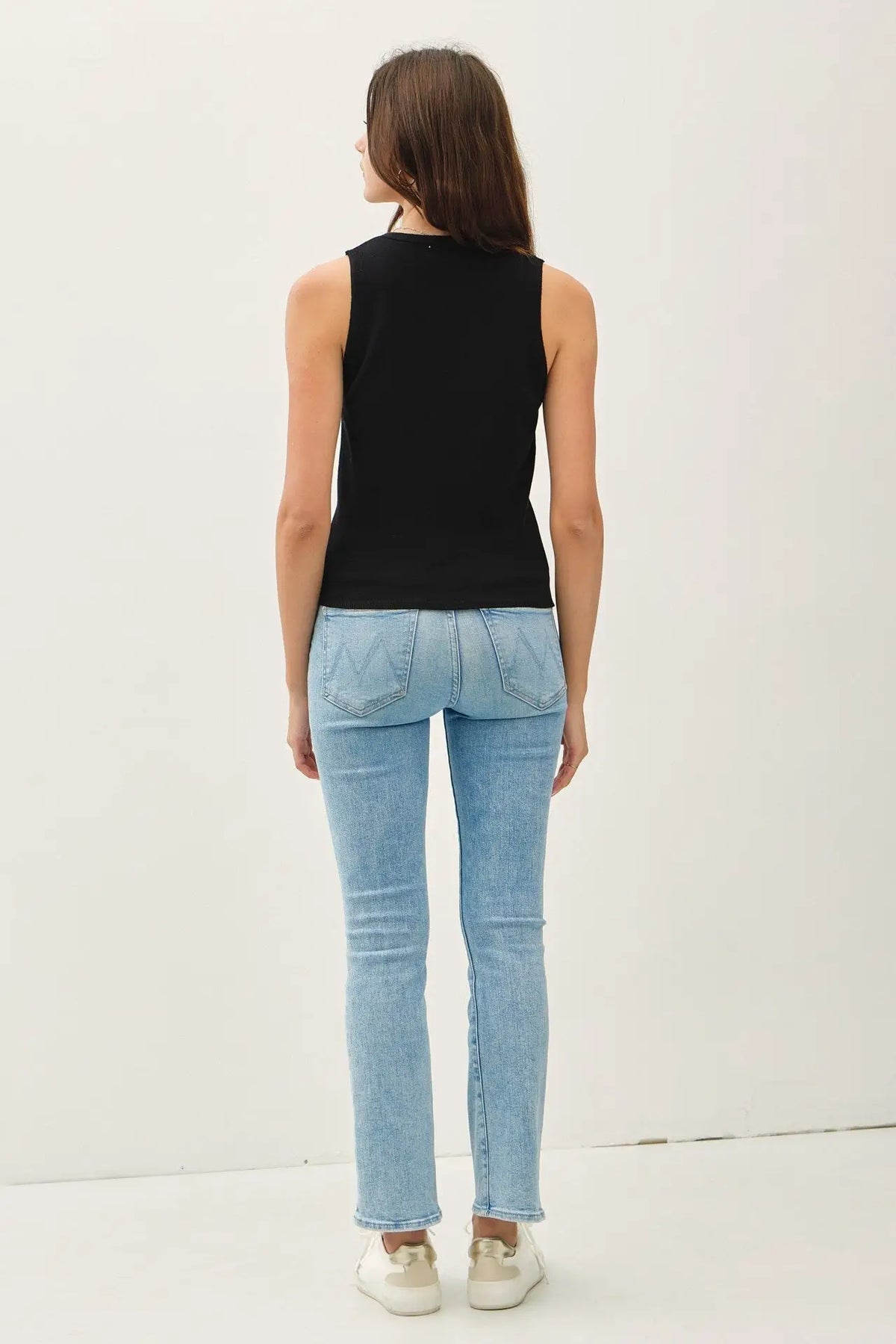 Woman in black sweater tank and light blue jeans, part of shop Daisy women’s boho chic clothing