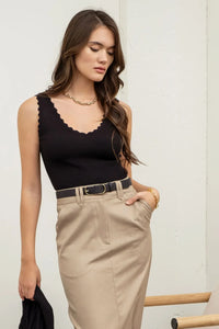 Woman in a black tank top and beige skirt showcasing a Scallop Edge Sleeveless design