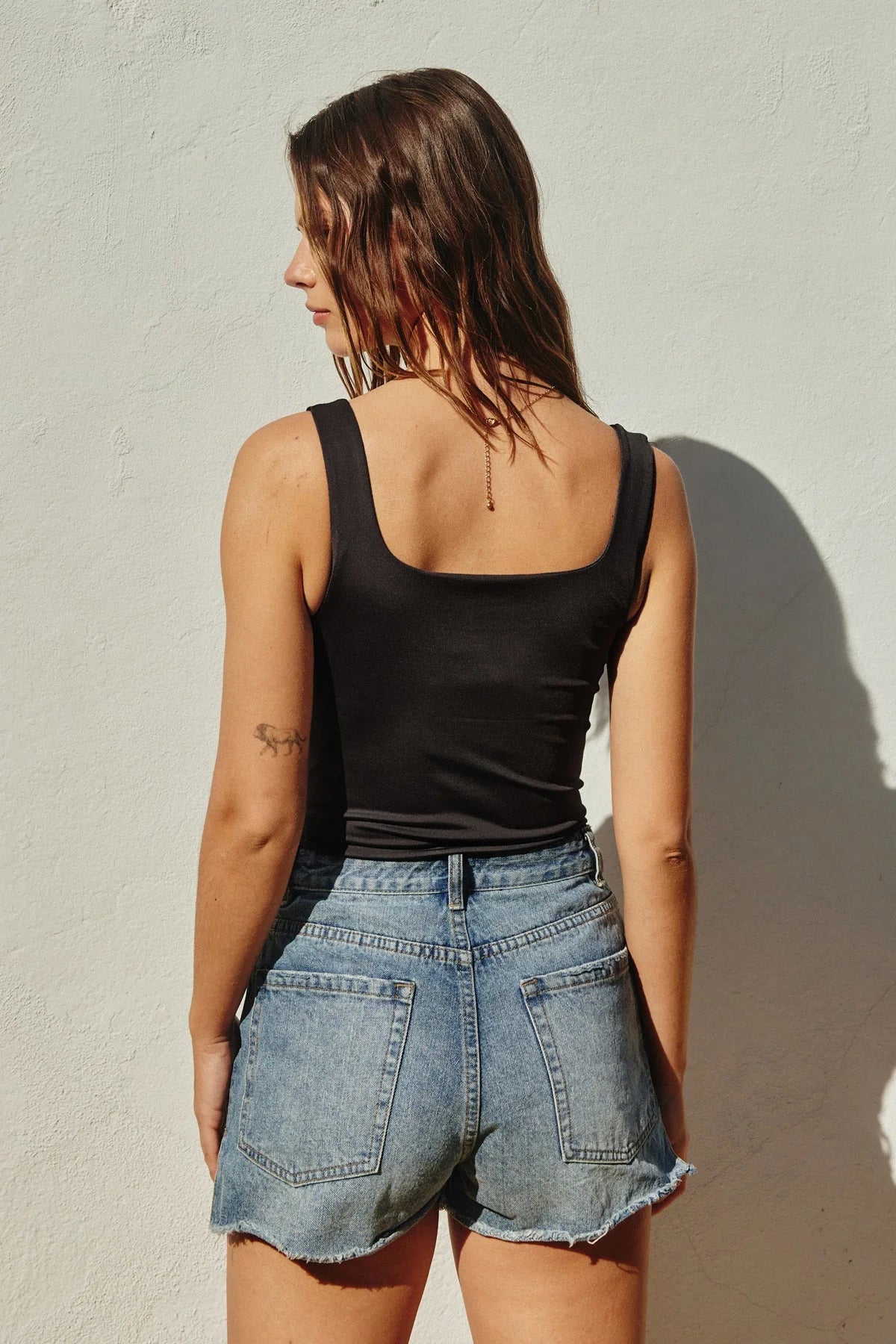 Woman in black tank top and denim shorts, exemplifying boho free spirit style