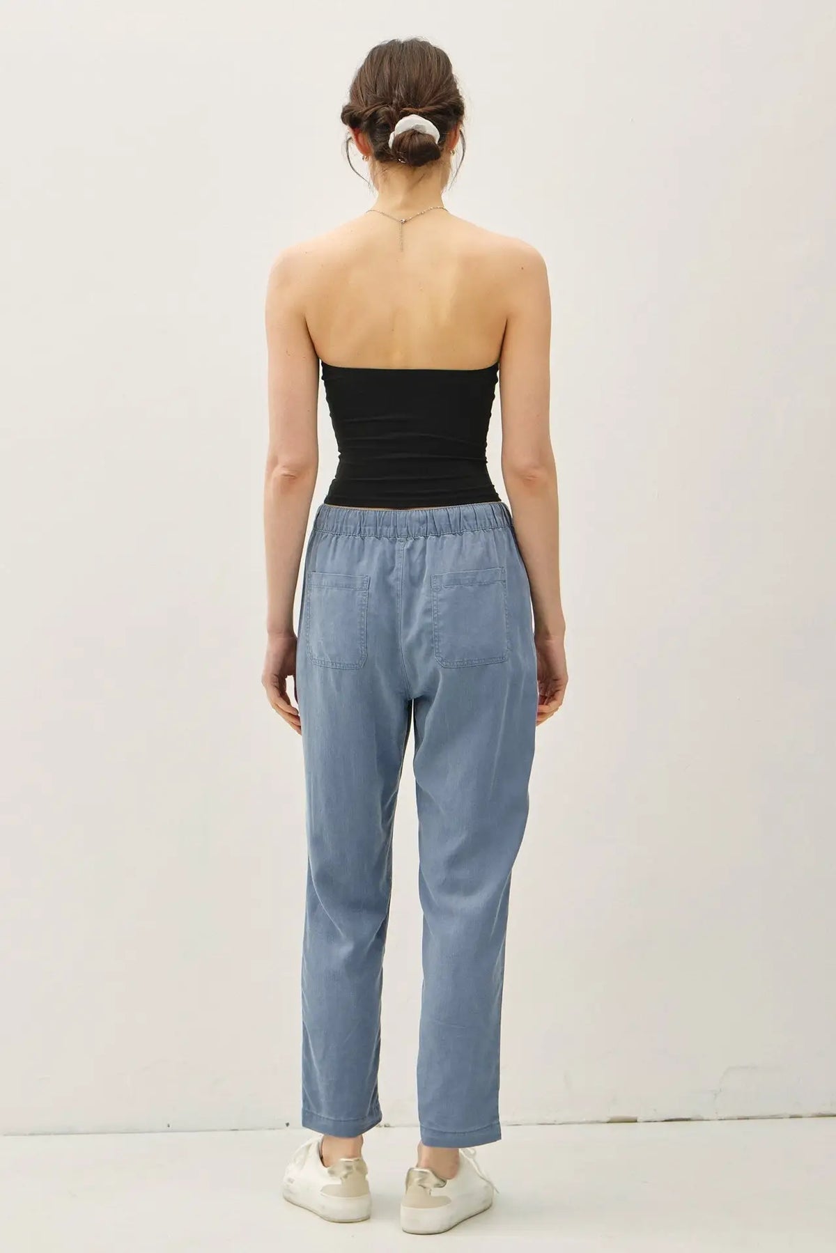 Woman wearing black tube top and blue TENCEL TAPERED PANTS for a stylish look