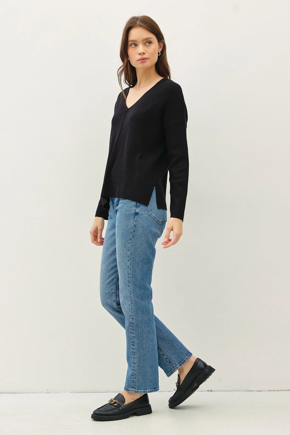 Woman in a black v-neck sweater with center seam and blue jeans showcasing boho style