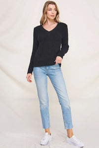 Woman wearing soft cloud ribbed V-neck pullover sweater with light wash jeans and white sneakers