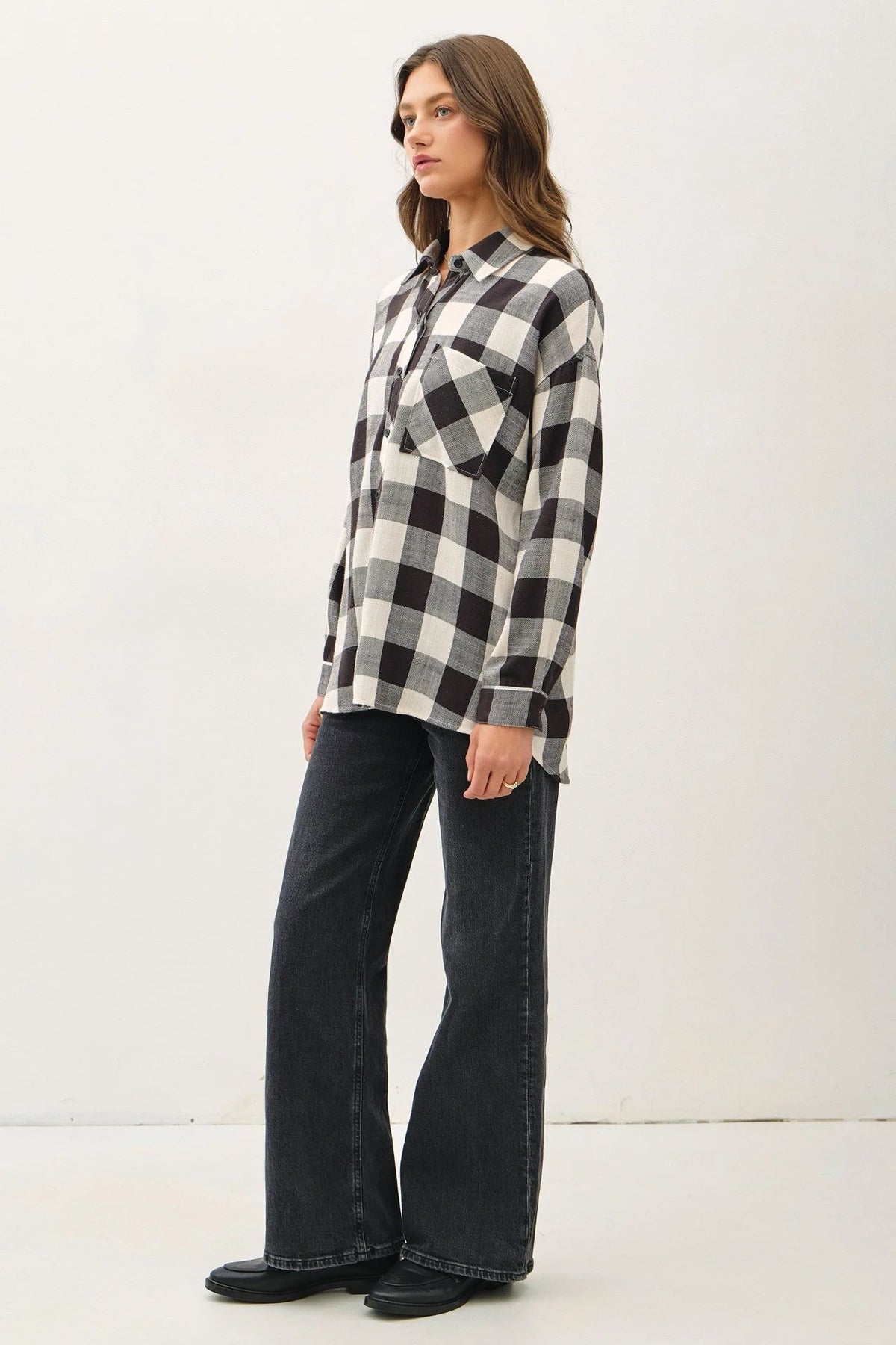 Woman in a black and white buffalo check flannel shirt and wide-leg pants