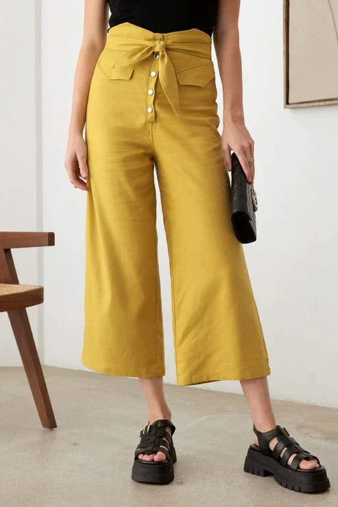 Woman wearing belted asymmetric waistband snap button pants with a black top