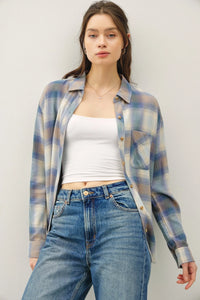 Woman wearing a vintage plaid boxy shirt over a white crop top and blue jeans