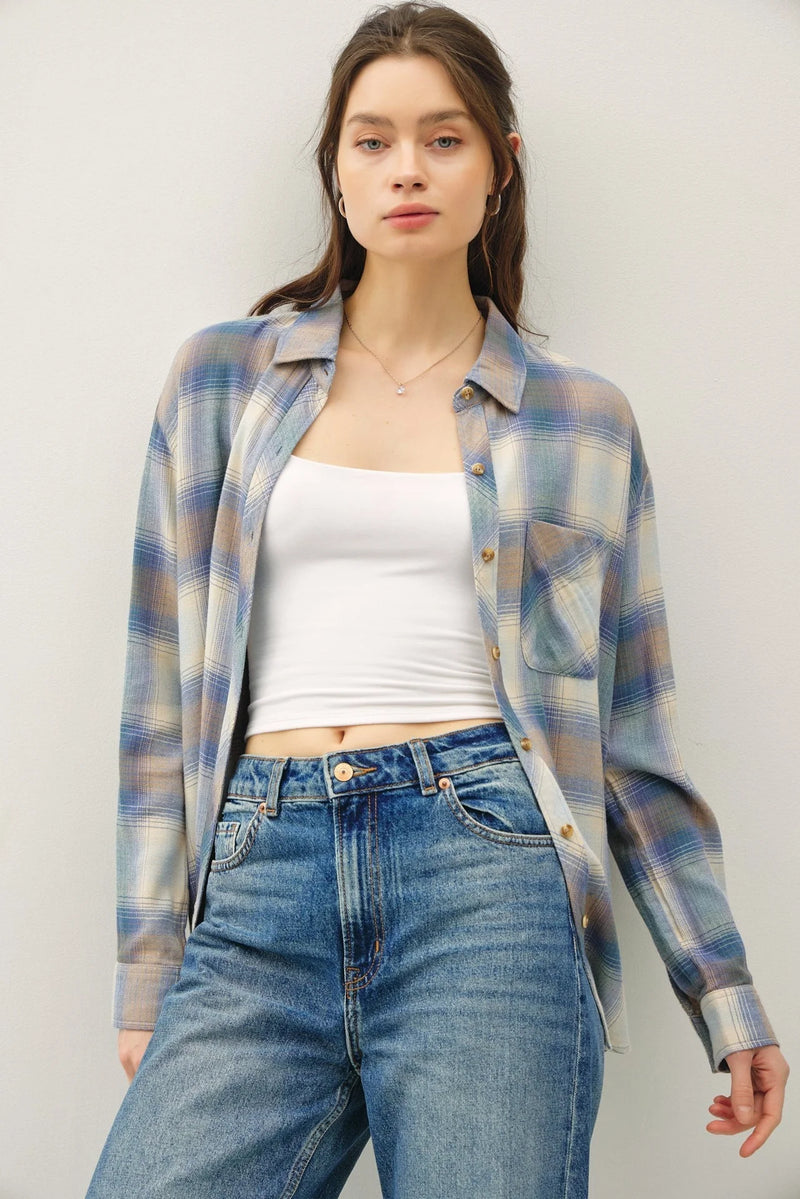 Woman wearing a vintage plaid boxy shirt over a white crop top and blue jeans