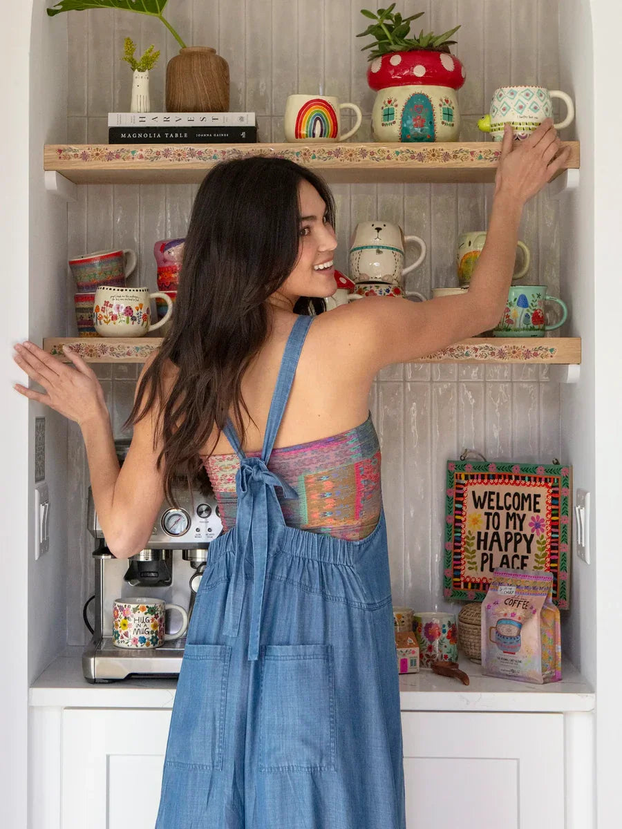 Woman in a blue denim dress reaching for items on shelves, embodying free spirit boho style