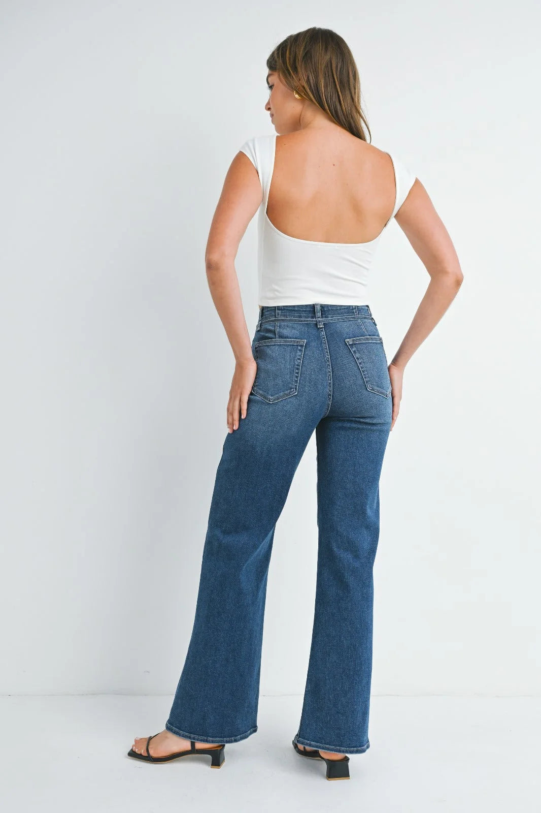 Woman in blue flared jeans and white top showcasing JUST BLACK dark denim belted wide leg